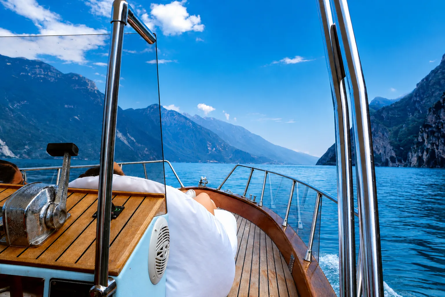 Relax sul ponte in legno della barca durante la navigazione sul Lago di Garda, tra le montagne dell'Alto Garda